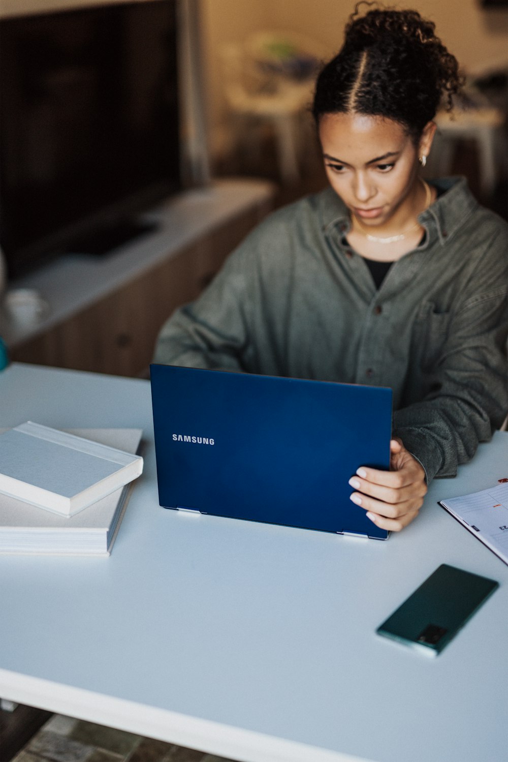 Femme en veste grise tenant un ordinateur portable bleu
