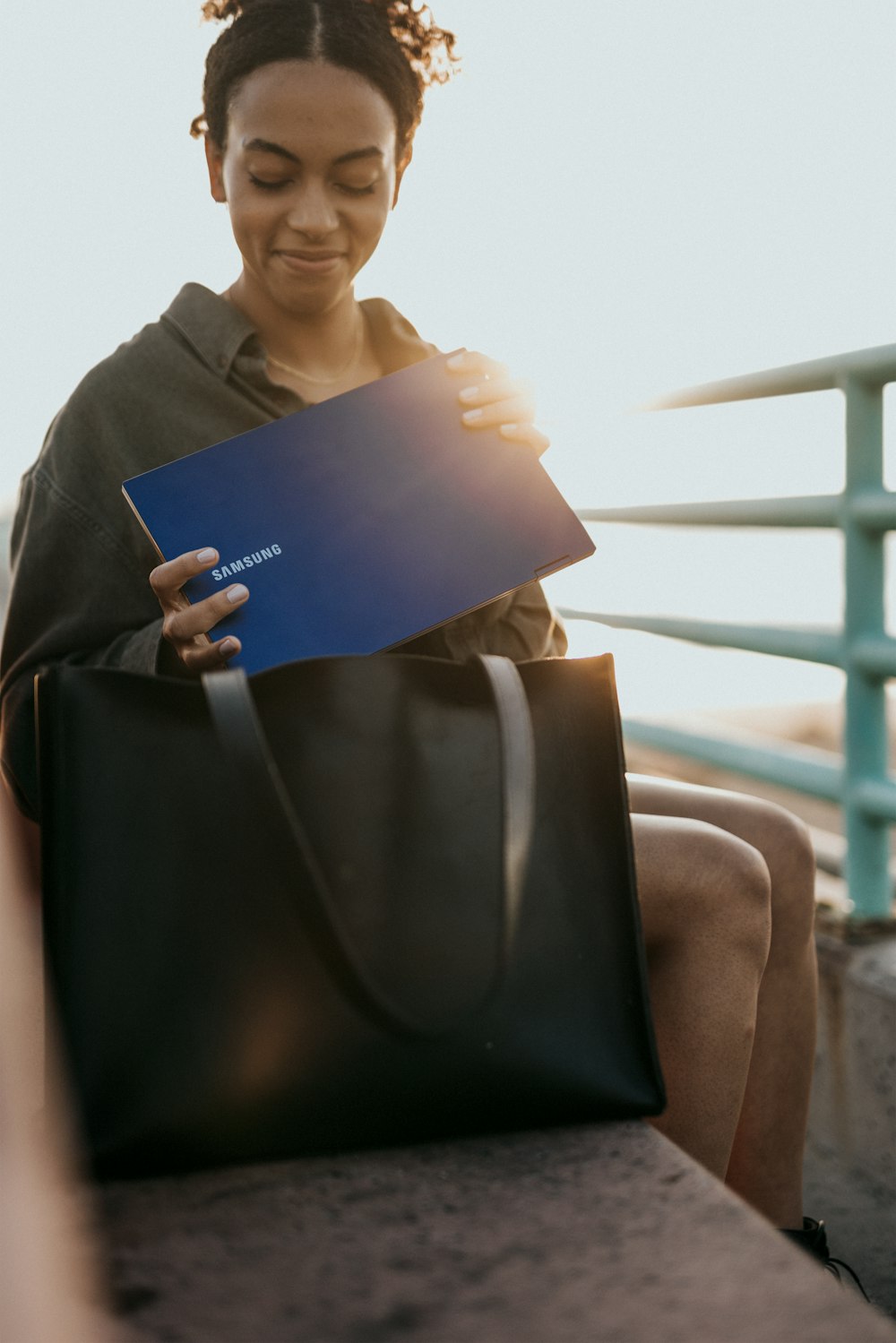 woman in brown coat holding blue laptop