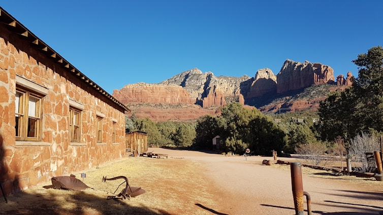 A dignified stone building bathed in warm Arizona sunlight, framed by desert mountains and a clear blue sky.