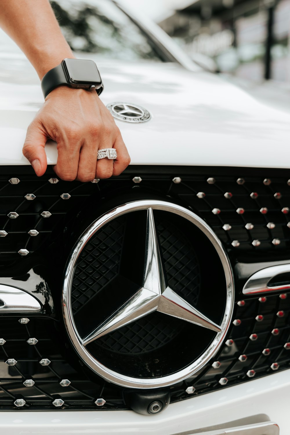 person holding silver mercedes benz emblem