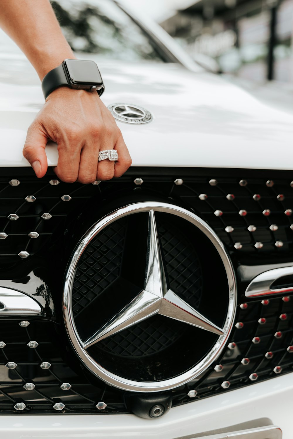 Persona sosteniendo el emblema plateado de Mercedes Benz