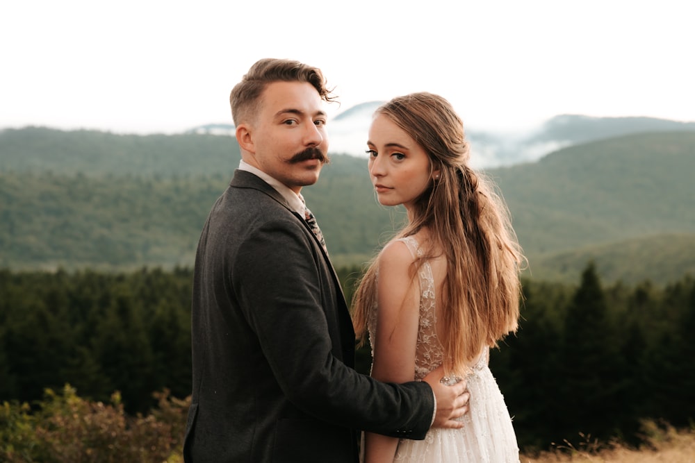 man in black suit jacket beside woman in white dress