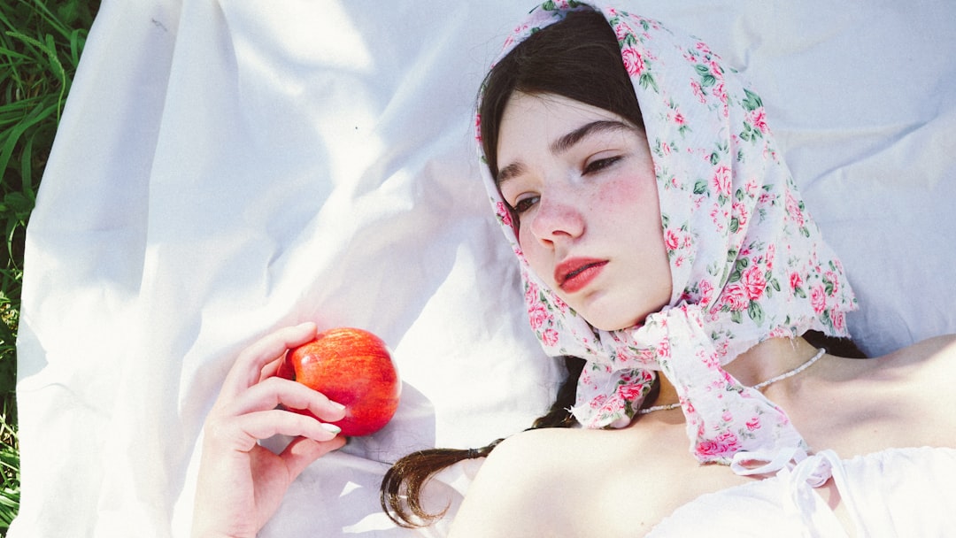 woman in white and red floral hijab holding red apple