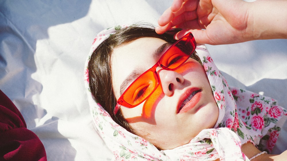 woman in red sunglasses lying on white textile