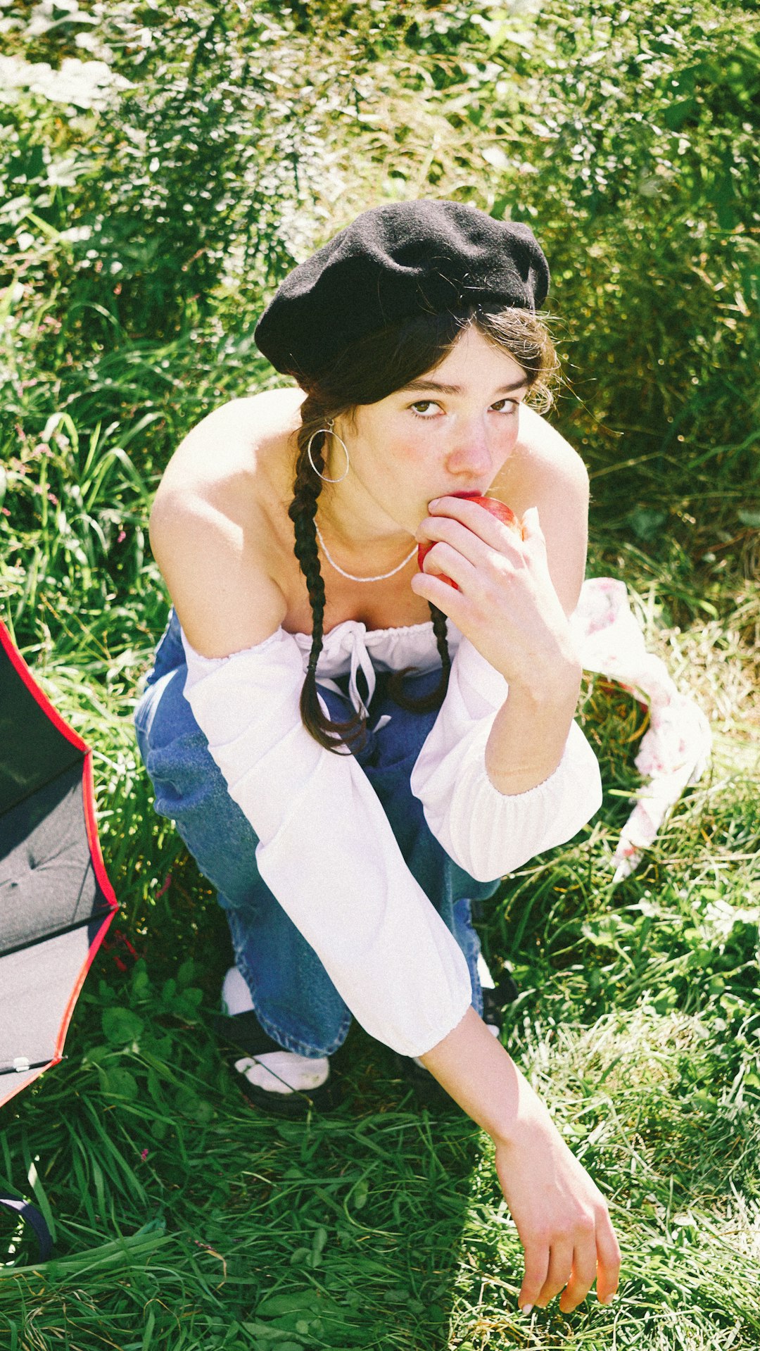 woman in white tank top and blue denim jeans sitting on green grass during daytime