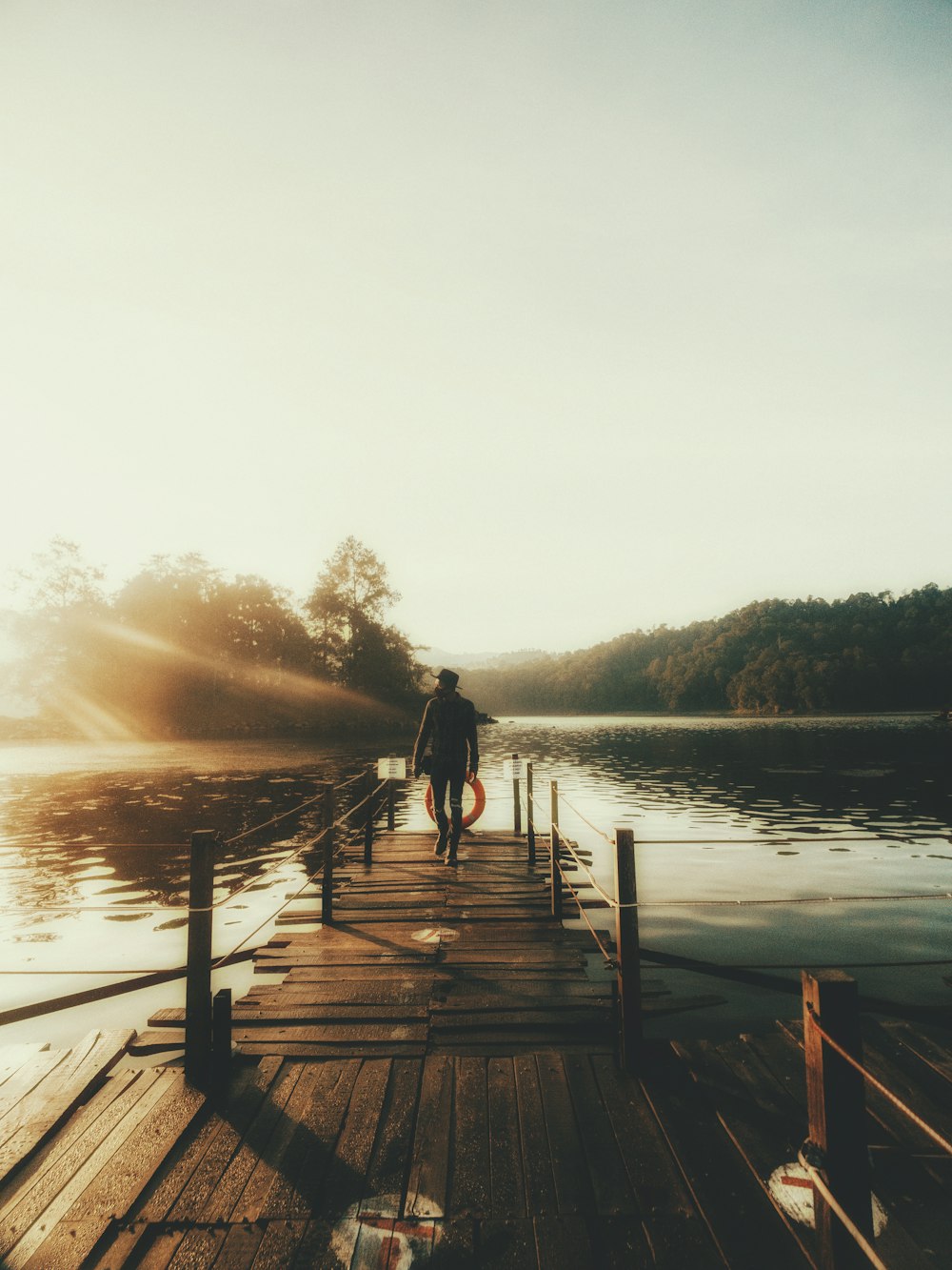 man in black jacket standing on brown wooden dock during daytime