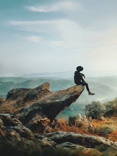 man in black jacket and black pants standing on brown rock formation during daytime