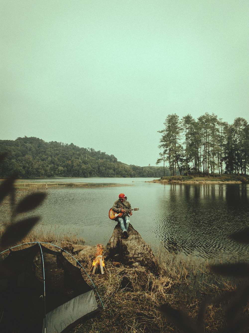 person sitting on rock near river during daytime