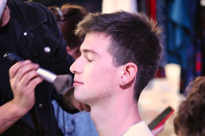 A bride having makeup applied gently with brushes by a professional artist.