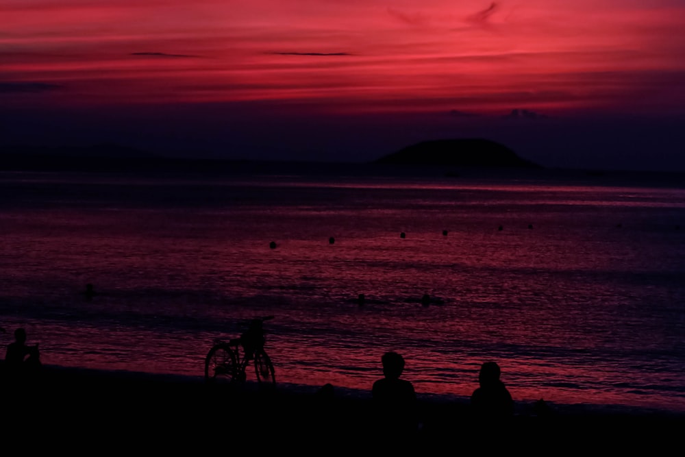 silhueta das pessoas na praia durante o pôr do sol