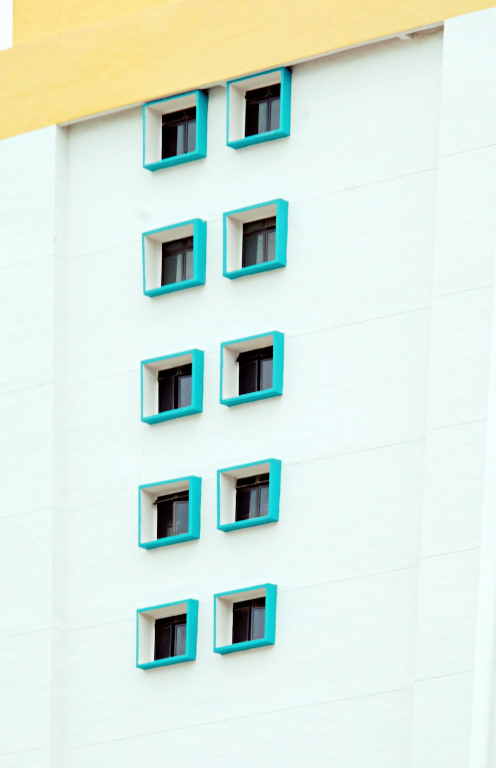 white concrete building with green windows