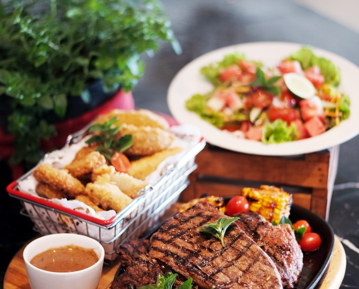 grilled meat with vegetable on brown wooden round tray