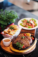 Close-up of a beautifully plated steak frites with fresh herbs on a rustic wooden table.