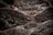 Wet, rough-textured stone surfaces are arranged in an irregular, interlocking pattern. The stones have a dark, almost black appearance with a glossy sheen due to water. The spaces between the stones are filled with lighter colored grout.
