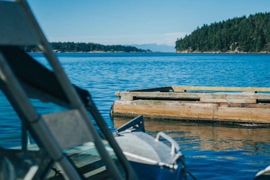 brown wooden dock on blue sea under blue sky during daytime in Mayne Island Canada