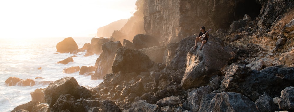 person in black shorts standing on rocky shore during daytime