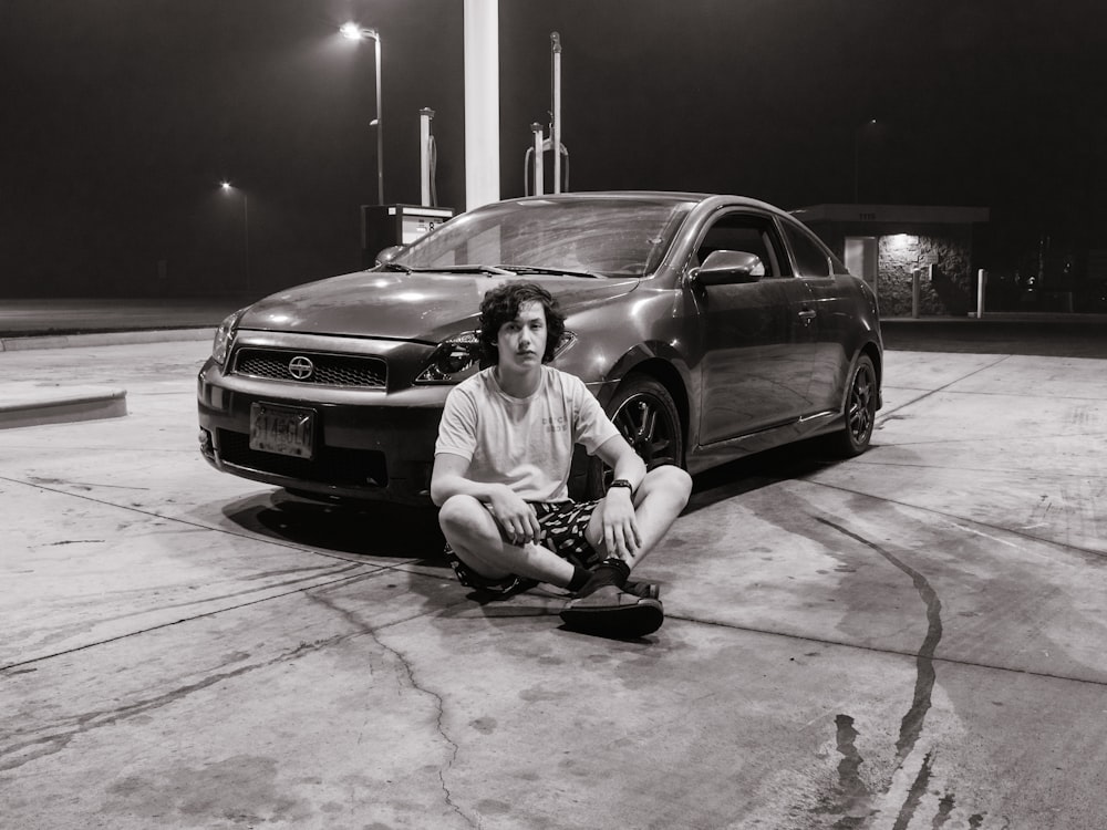 man in white shirt sitting beside black bmw m 3