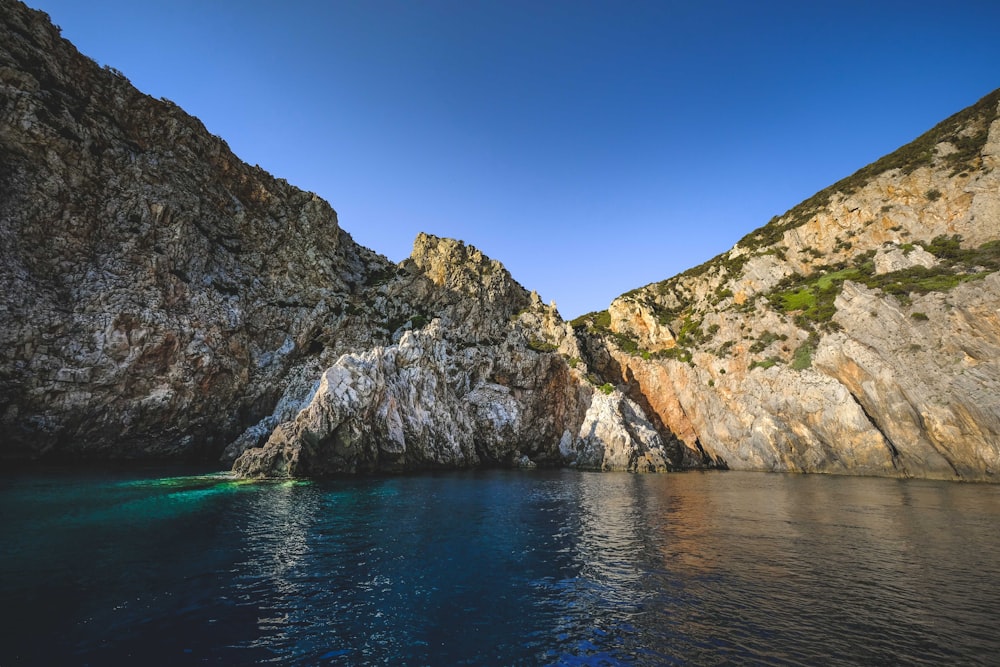 Montaña rocosa marrón junto al mar azul bajo el cielo azul durante el día