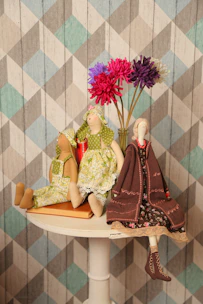 A vibrant scene showing dolls dressed in a variety of costumes on a rustic wooden table.