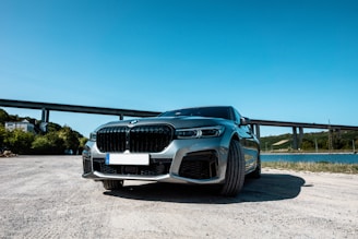 A modern car parked in a scenic location with a clear blue sky.