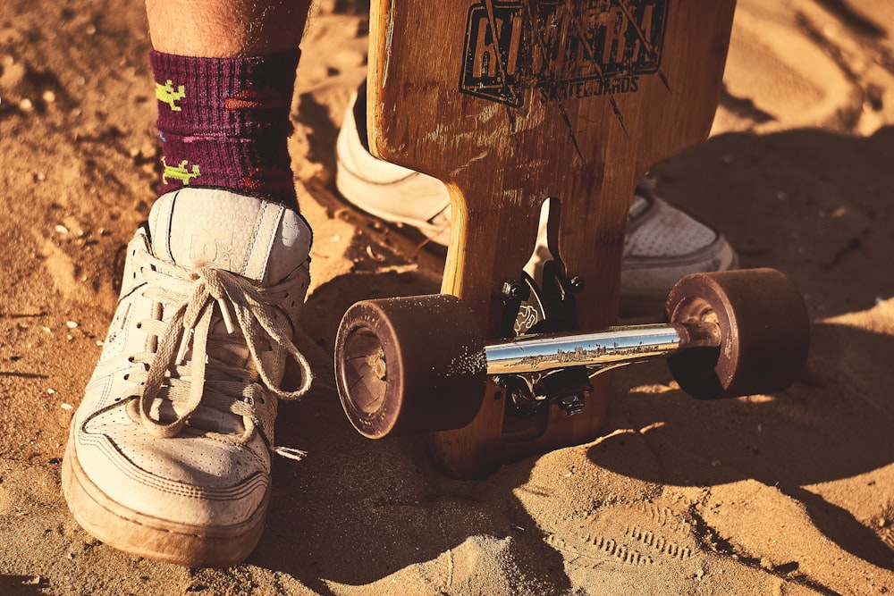 person in white shoes sitting on black and brown skateboard