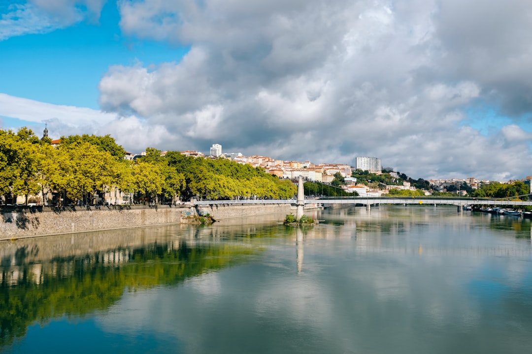 white and brown concrete building near body of water under white clouds and blue sky during