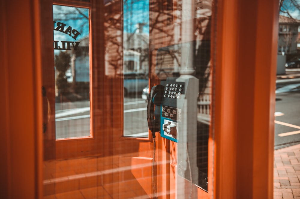 cabina telefónica negra frente a la ventana de vidrio