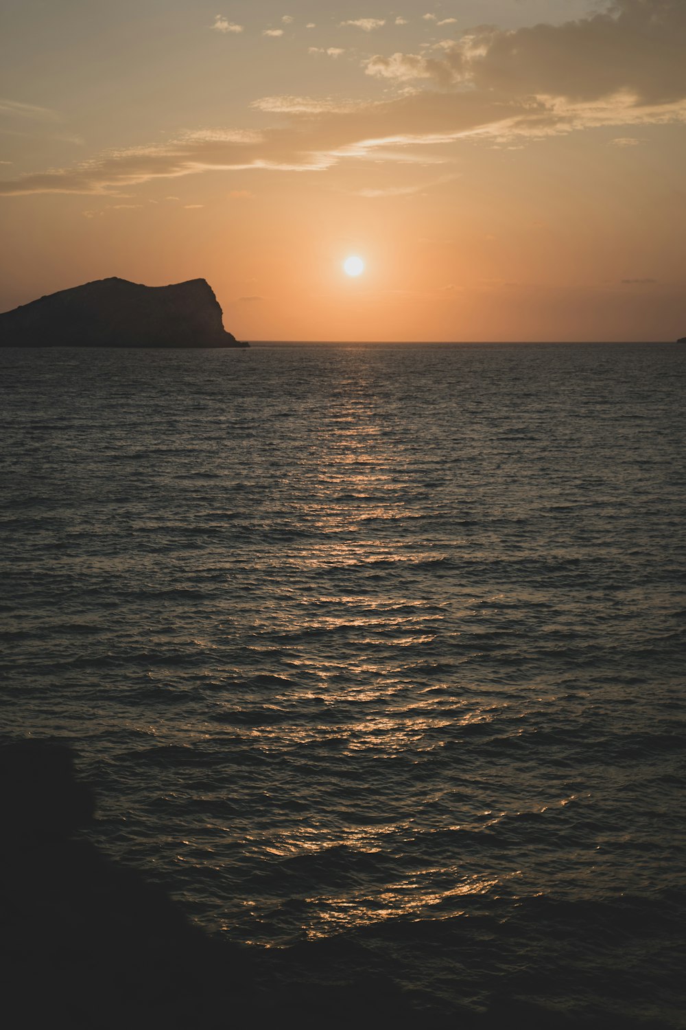 silhouette of mountain beside sea during sunset