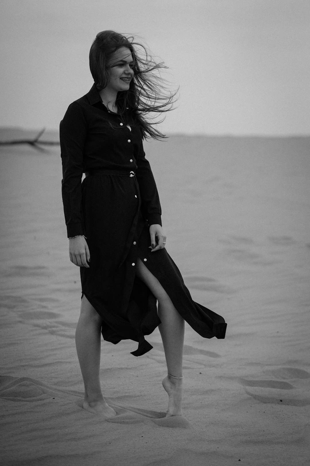 woman in black coat and black skirt walking on the beach