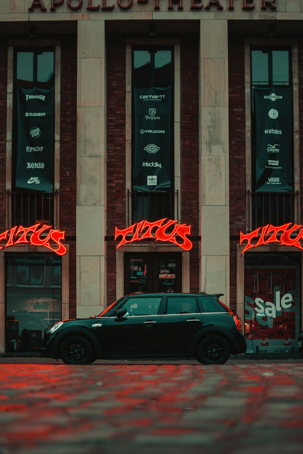 black sedan parked beside brown concrete building during nighttime