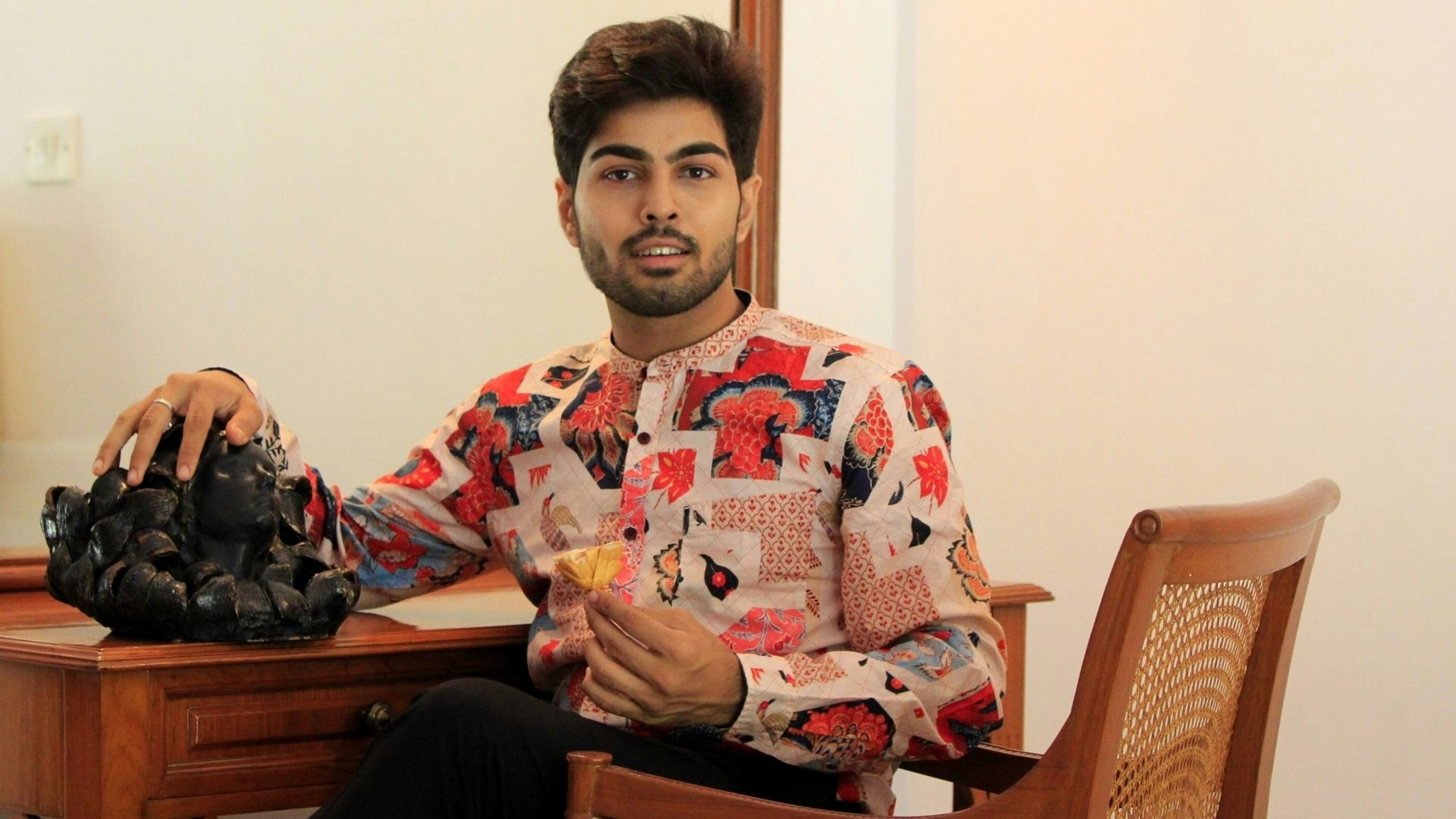 woman in white red and blue floral long sleeve shirt sitting on brown wooden chair