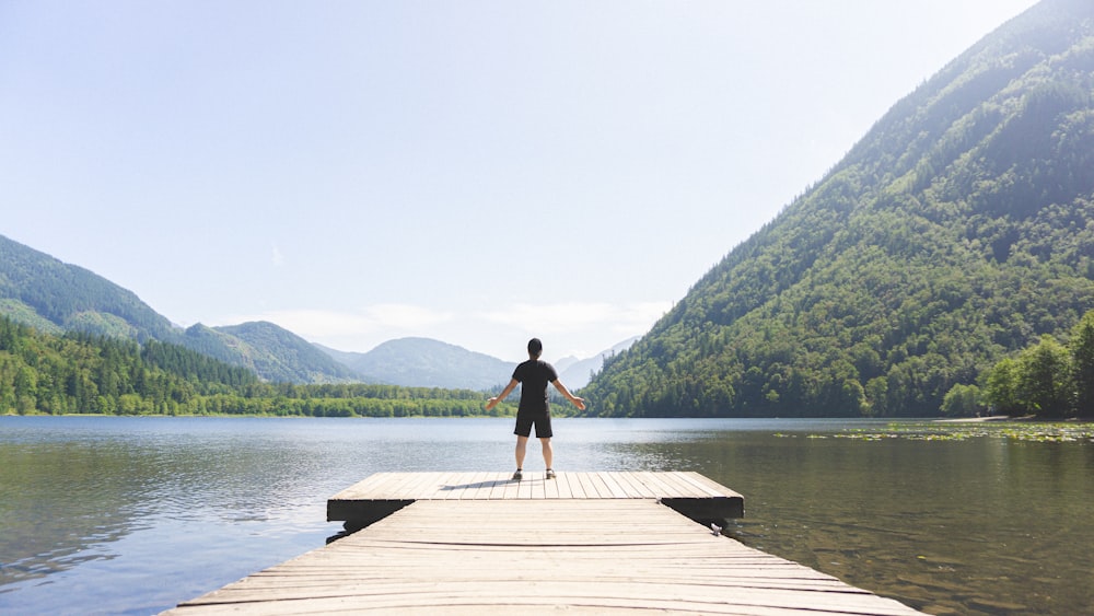 man in black shirt standing on wooden dock during daytime