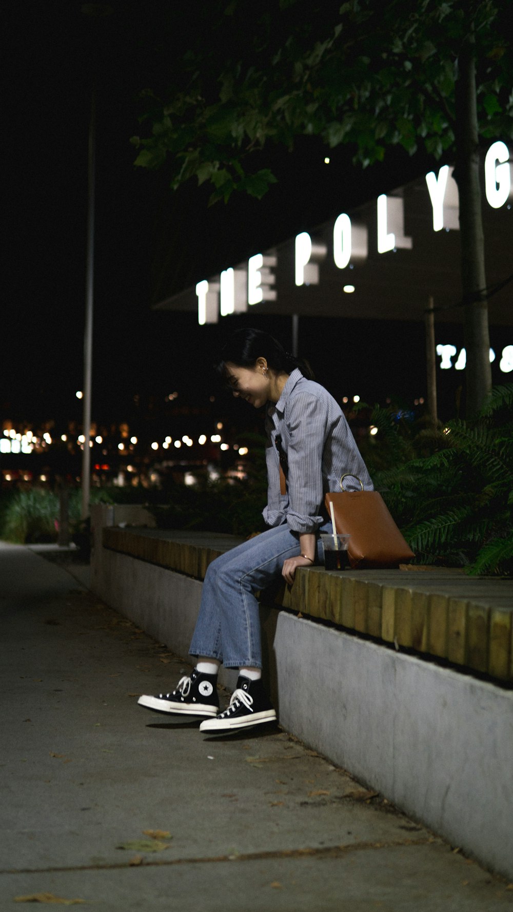 man in blue denim jacket and blue denim jeans sitting on concrete bench during night time