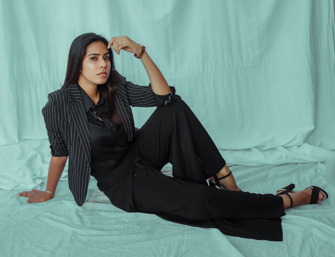 woman in black and white stripe dress shirt and black pants sitting on white bed