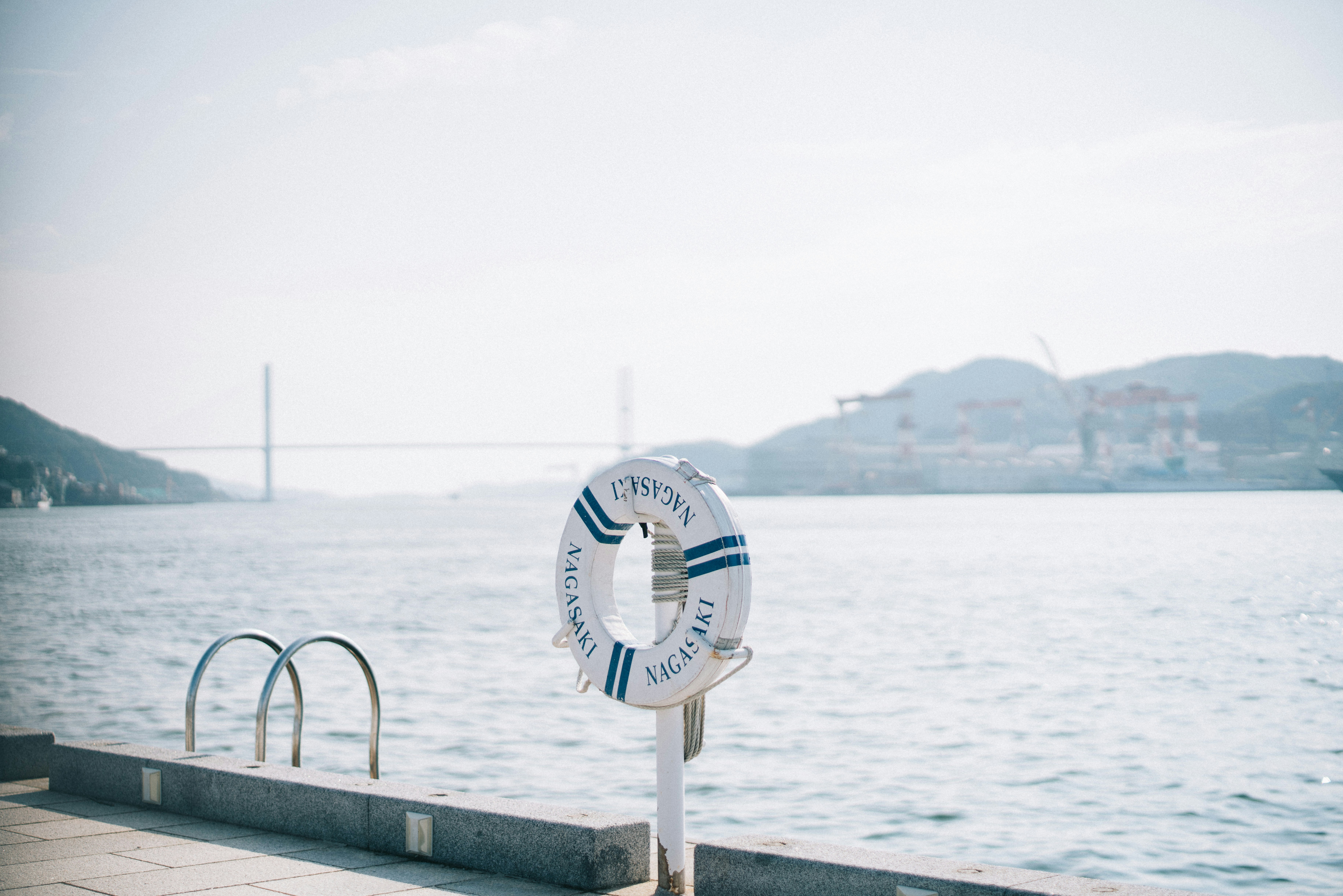 white and blue round analog watch on gray metal railings near body of water during daytime