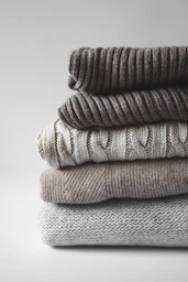 Stack of neatly folded monochrome sweaters with soft textures