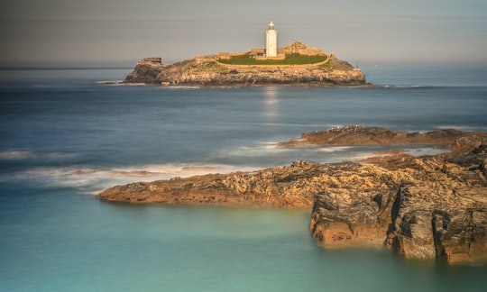 white lighthouse on brown rock formation near body of water during daytime in Godrevy United Kingdom