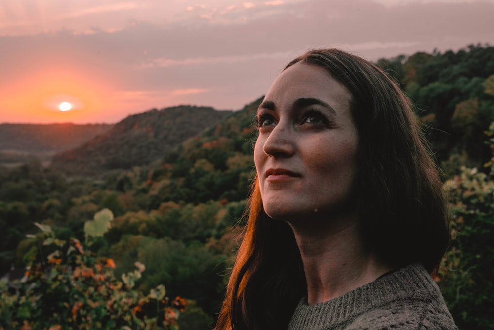 woman in gray knit shirt standing near green plants during daytime