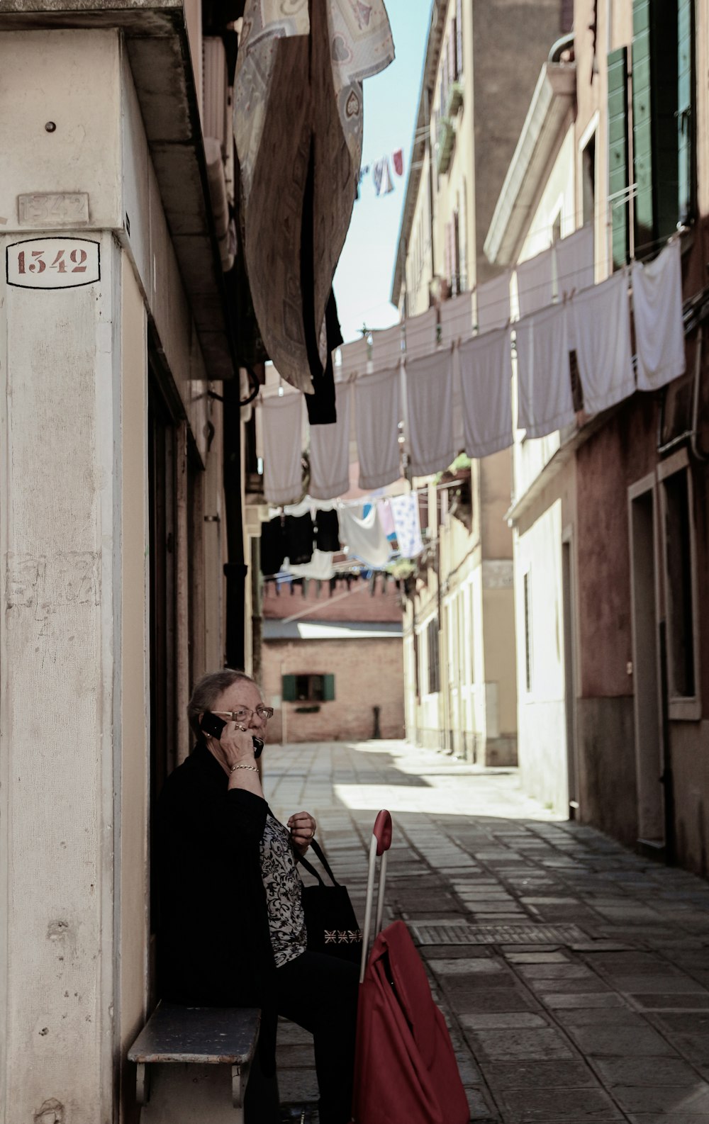 man in black jacket sitting on chair near building during daytime