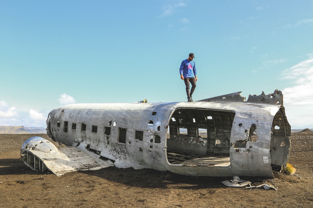 man in blue shirt and black pants standing on white airplane