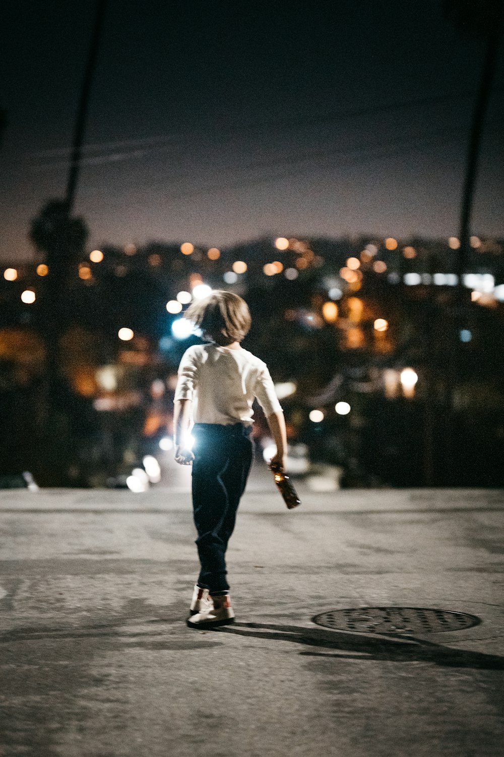 girl in white shirt and blue denim jeans walking on street during night time