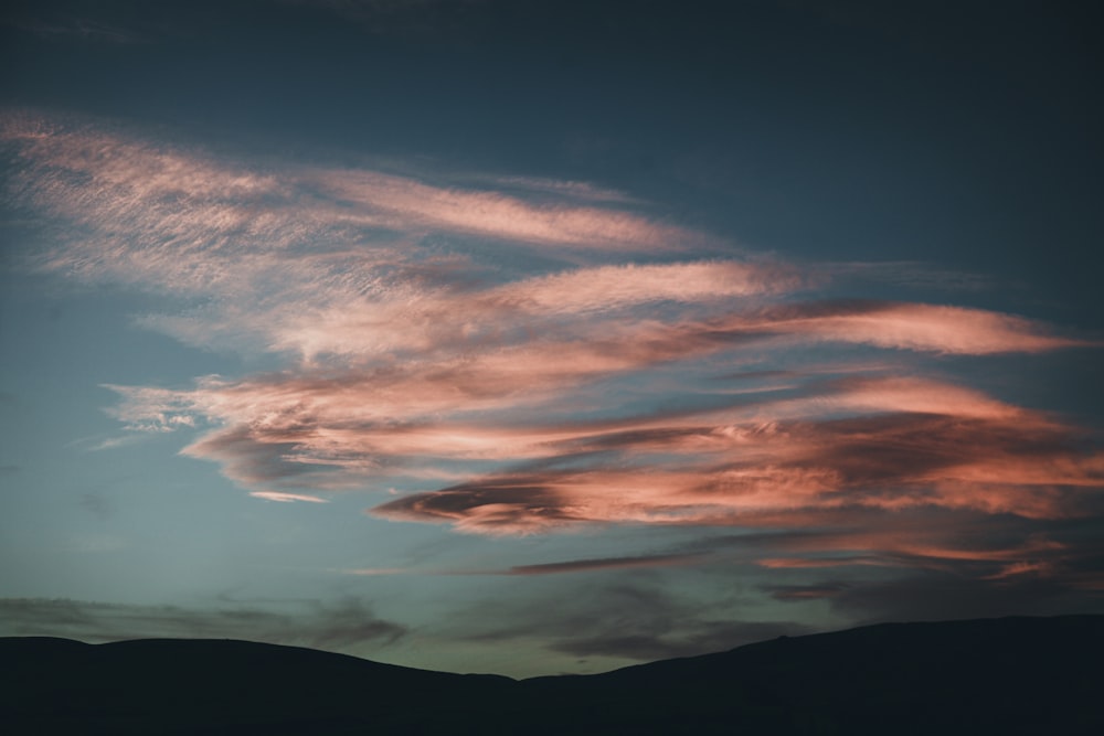 silhouette of mountain under cloudy sky during sunset