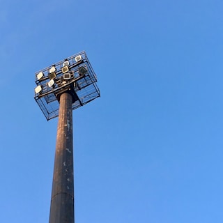 A rugged light tower standing tall on a mining site, casting wide light over heavy machinery and workers.