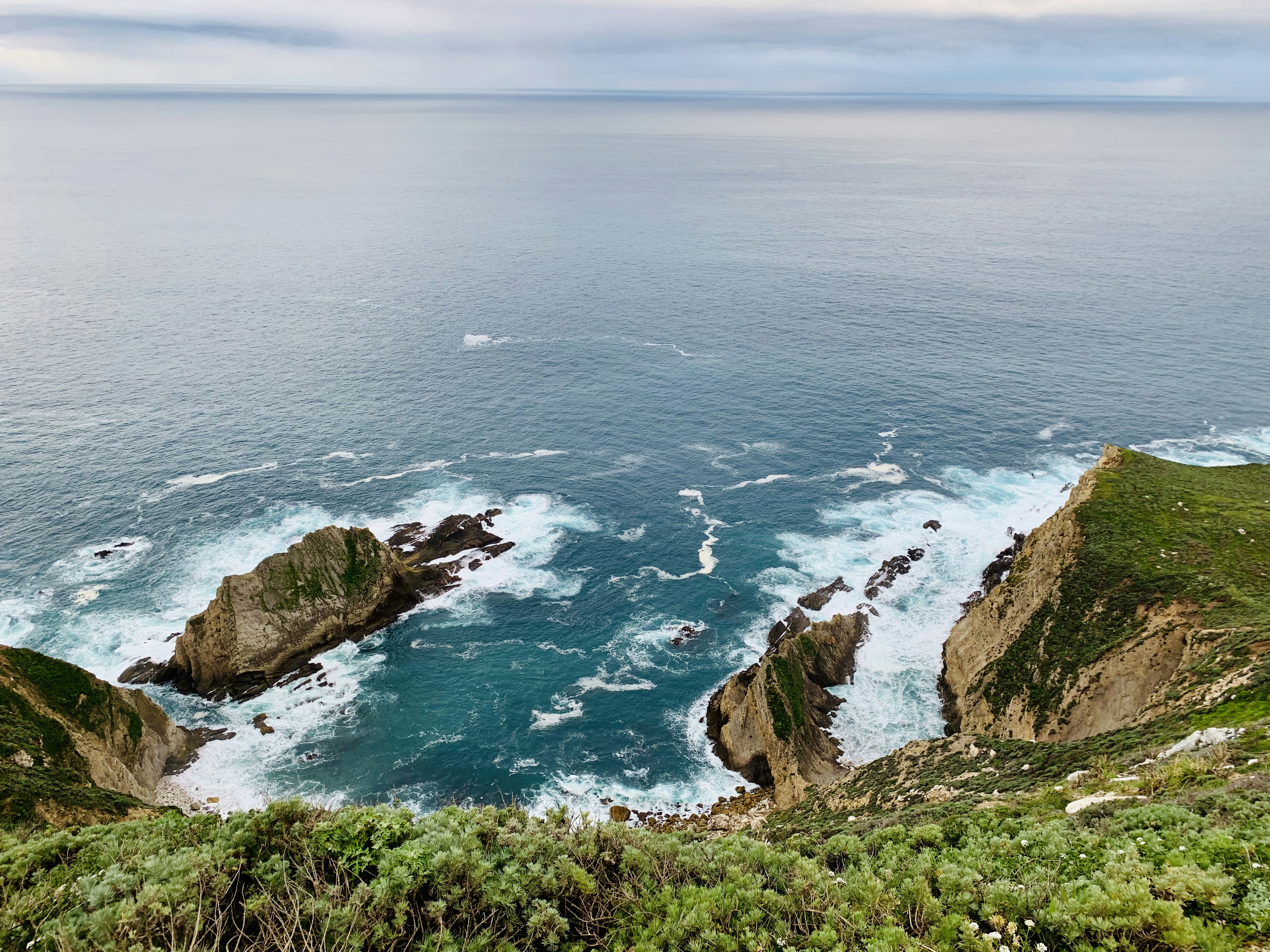 aerial view of green and brown mountain beside blue sea during daytime