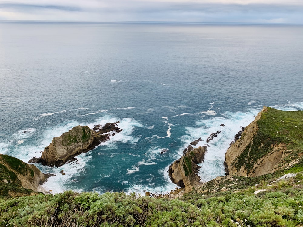 Vista aérea de la montaña verde y marrón junto al mar azul durante el día