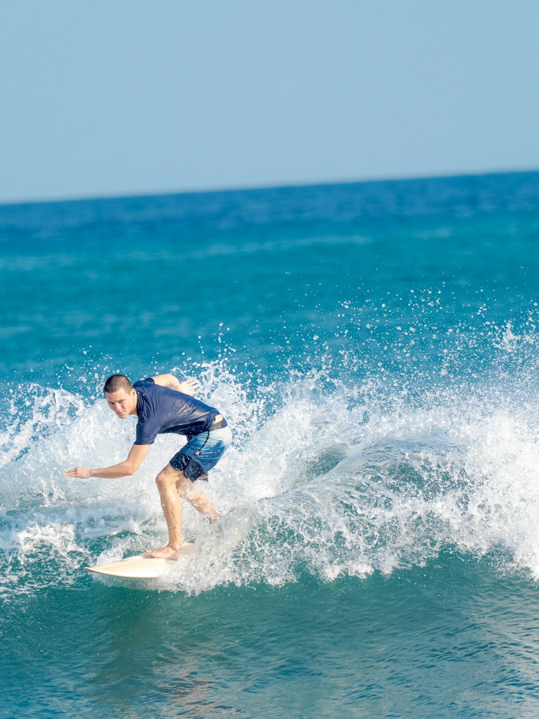 man in blue shirt surfing on sea waves during daytime