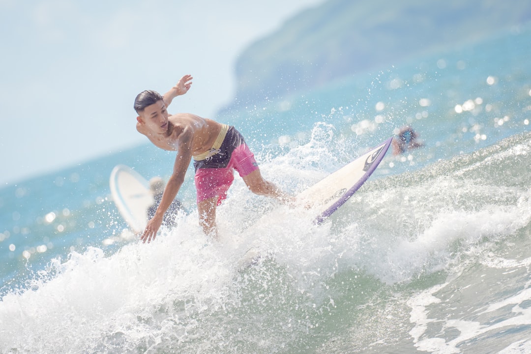 man in pink shorts surfing on sea waves during daytime