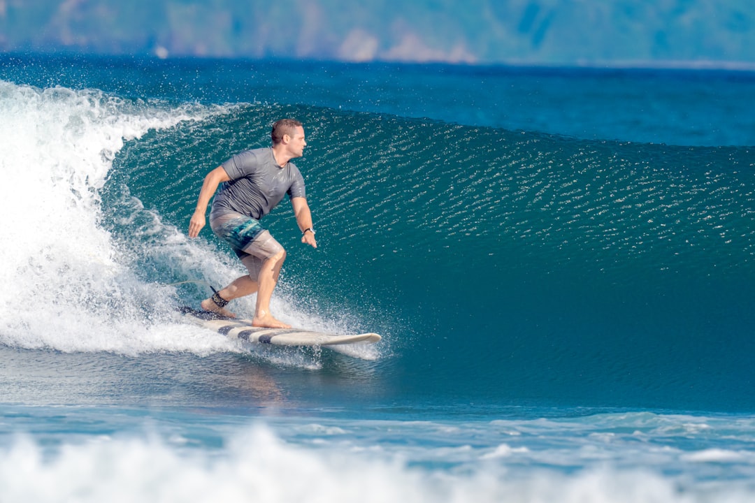 man in blue shirt surfing on sea waves during daytime