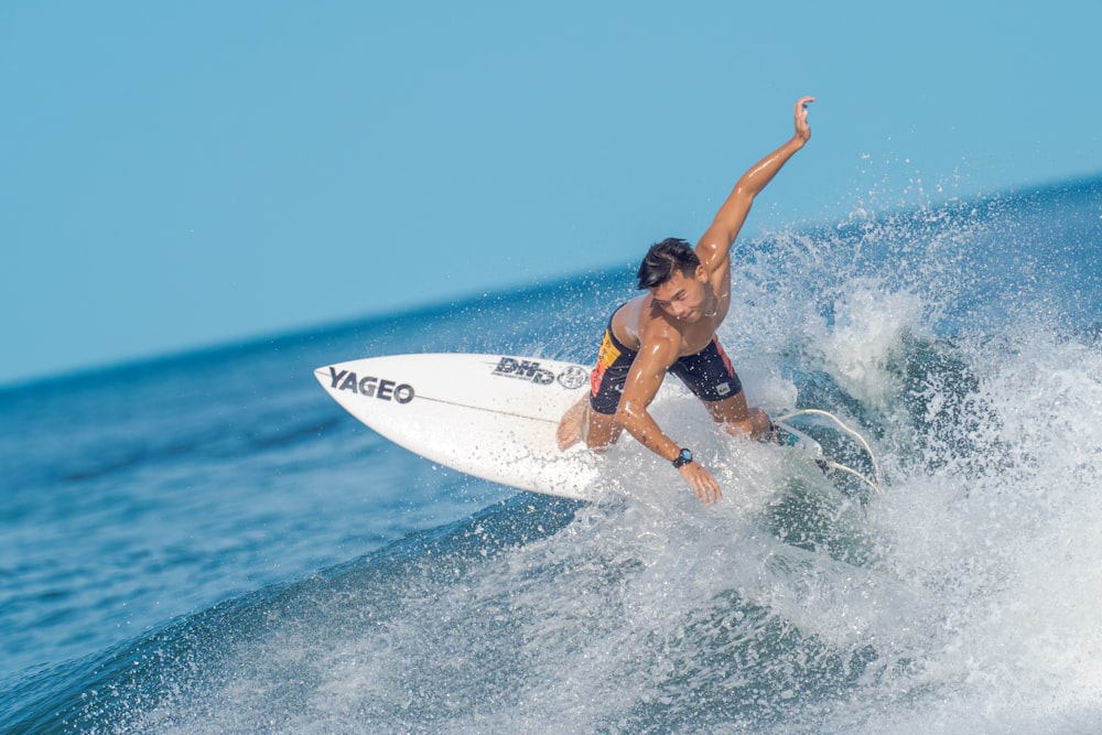 man in blue shorts surfing on sea during daytime