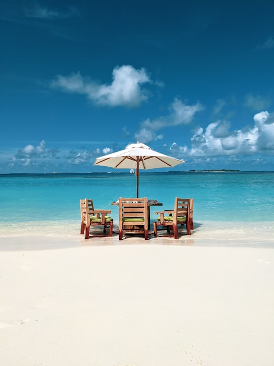 brown wooden chairs on beach during daytime in Baa Atoll Maldives
